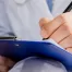 healthcare nurse writing information on a piece of paper on a blue clipboard