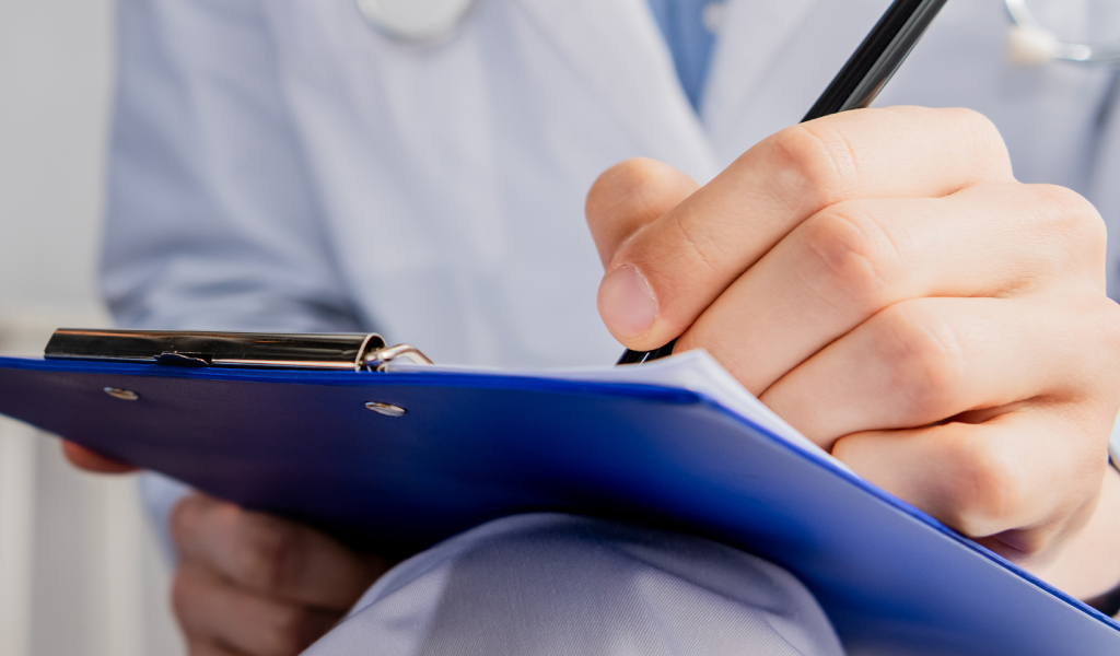 healthcare nurse writing information on a piece of paper on a blue clipboard