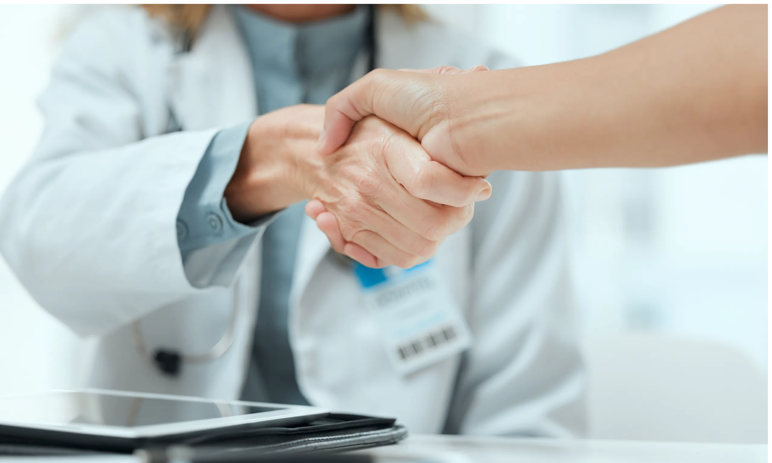 Health care professional shaking hands with another individual.