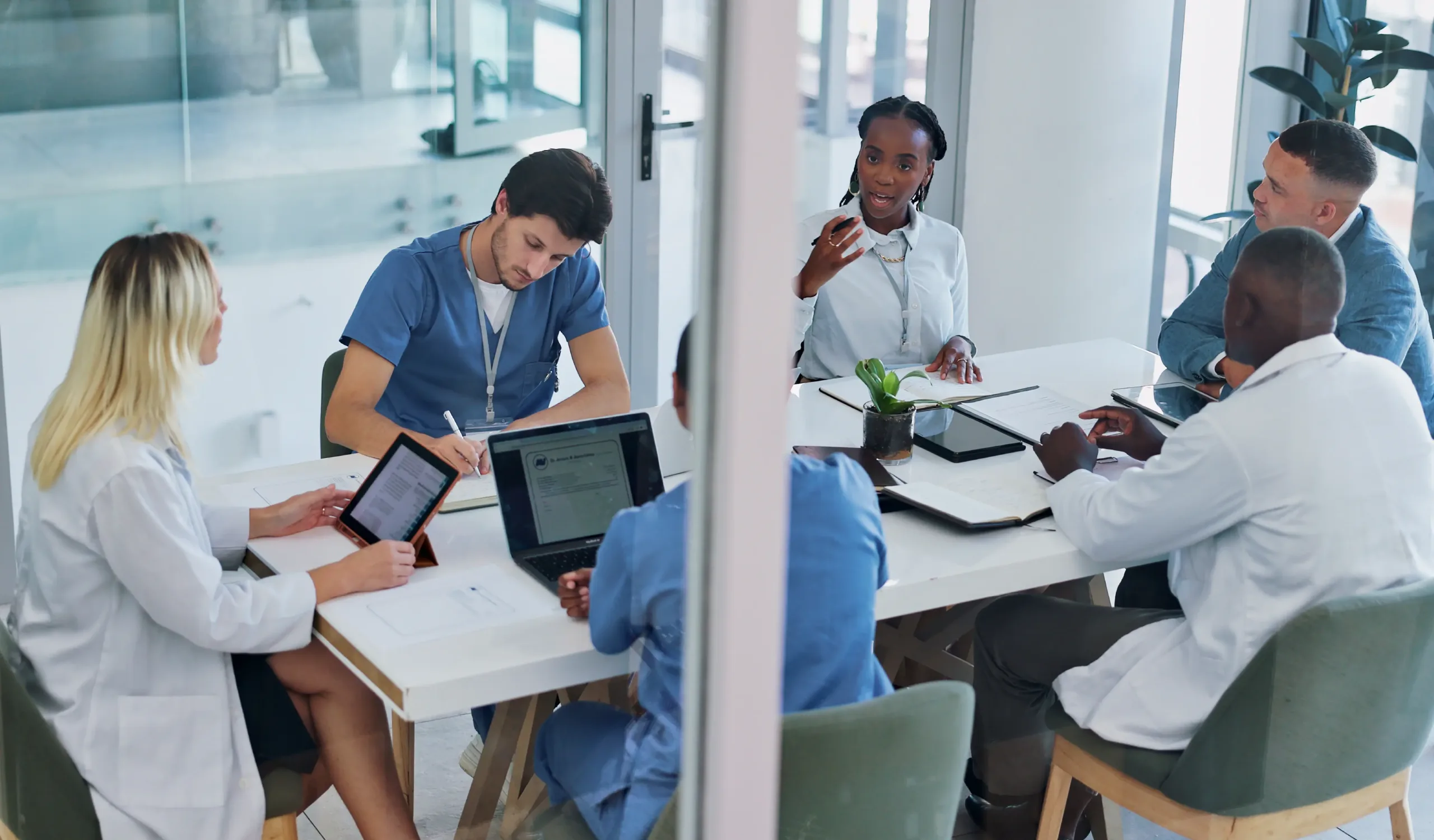 A diverse group of healthcare professionals and HR staff collaborate in a modern conference room during a strategy meeting.